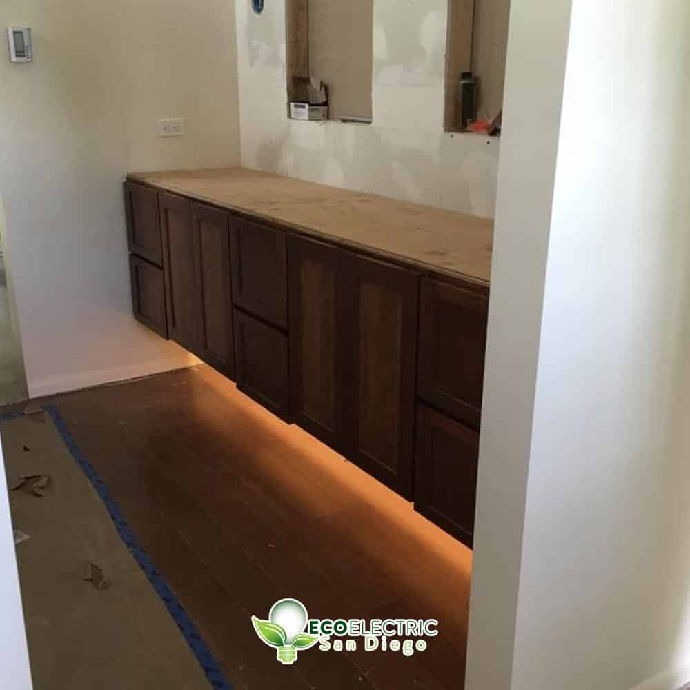 Recessed lighting under a bathroom cabinet during a remodel